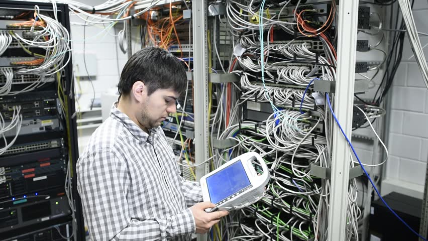 Technician is checking server wires in data centre using professional tablet