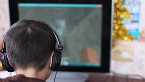 European white boy in headphones playing the computer game minecraft. the concept of gambling addiction, computer addiction. selective focus