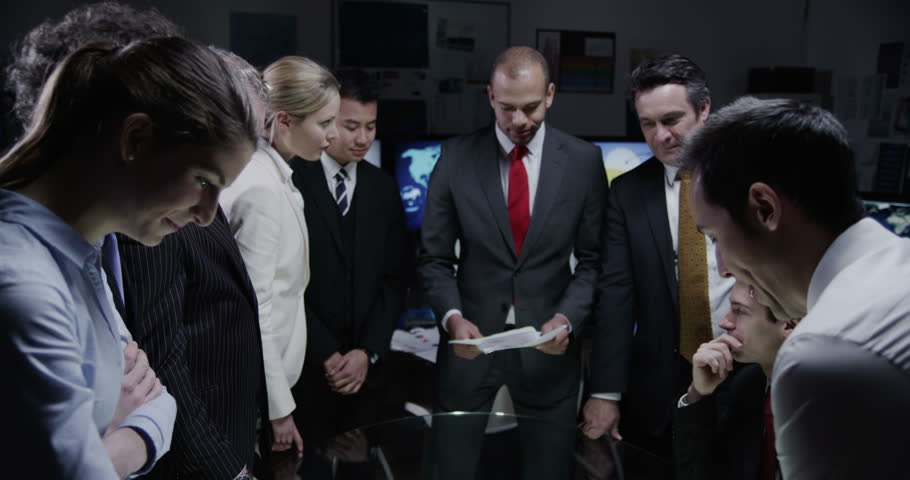 4k / Ultra HD version A diverse team of financial traders are working late in a dark room full of computer screens. They are watching world markets and doing deals over the phone. In slow motion.  | Shutterstock HD Video #14050970