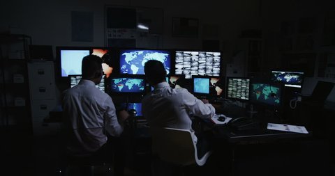 4k / Ultra HD version Two male security workers are going about their business in a busy system control room. This could be a meteorological weather station or airport traffic control room.