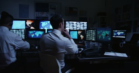 4k / Ultra HD version A team of male security personnel are manning the stations within a busy system control room. This could be a weather station or airport traffic control room. In slow motion. 