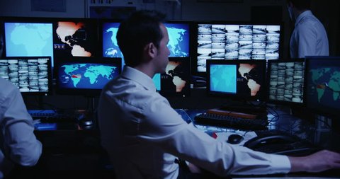 4k / Ultra HD version A team of male security personnel are manning the stations within a busy system control room, filled with computers. This could be a weather station. Shot on RED Epic