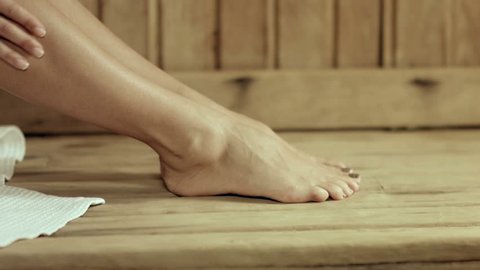Beautiful well-groomed woman's bare feet in the sauna, girl rubbed oil into the skin