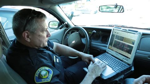 Anaheim, CA., January 2016: Policeman typing on a his laptop in his patrol car
