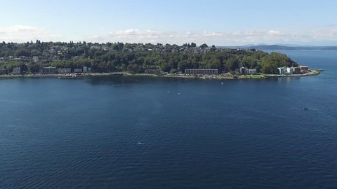 Aerial shot flying towards Bainbridge Island outside of Seattle, WA. Other island shores in the distance while boats and kayakers go by in the water below.