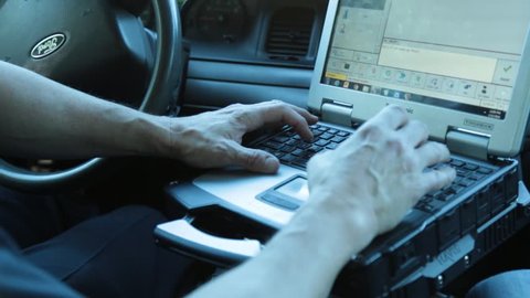 Anaheim, CA., January 2016: Police man typing on his laptop inside his patrol car