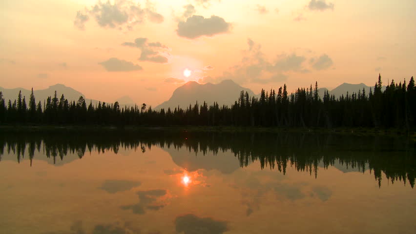 Time lapse of sun setting over alpine lake