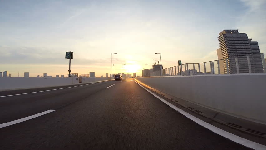 Driver's point of view across the bridge towards the climbing sunshine over the city horizon. Part 3. Eastbound over the Rainbow Bridge towards Daiba. | Shutterstock HD Video #14059466