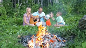 happy family sitting by the fire in the forest and having fun together