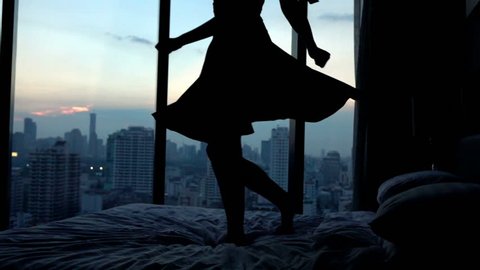 Young happy woman in dress dancing on hotel bed, super slow motion, 240fps
