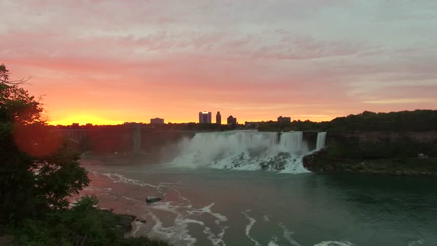 Aerial shots above Niagara Falls in the morning light. Drone flying above the mighty Niagara Falls on the Canadian side for sunrise view. Flying over Horse Shoe Falls and the Niagara River.