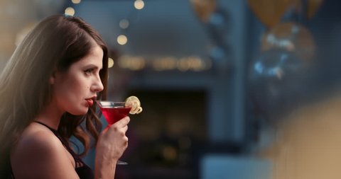 Beautiful woman drinking cocktail alone at glamorous party sad and alone at sexy fashion new year's eve event
