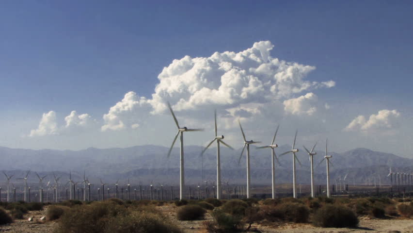 Hundreds of speedy windmills under time lapse desert clouds.