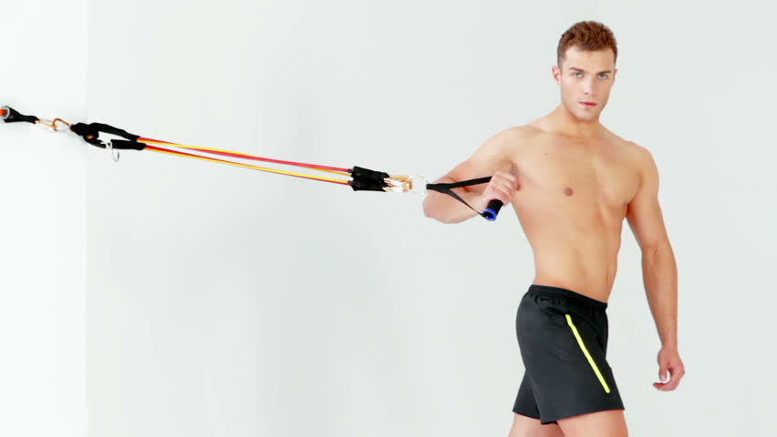 Handsome muscular man exercising with rubber on white background