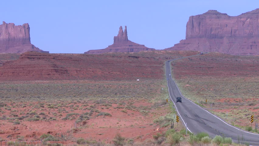 Vehicles drive past monument valley in Utah