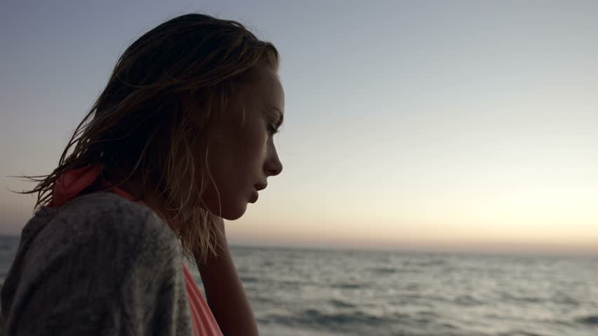 Girl relaxes near the sea admiring the sunset