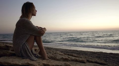 Young woman admires the sunset after swimming in the ocean in the evening Video Stok