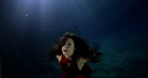 4k / Ultra HD version Beautiful mysterious woman underwater with flowing brunette hair and a red satin dress. Shot on RED Epic