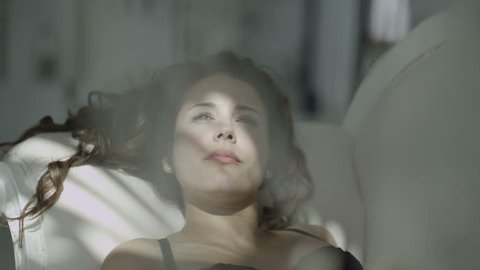4k / Ultra HD version Beautiful brunette model in black lingerie reclines on a chaise and relaxes in the sunlight from the window. Shot on RED Epic