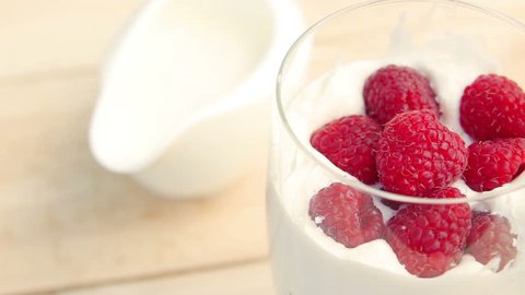 Raspberry falls in a glass of milk. Milk shake.
