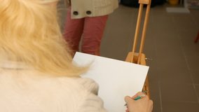 Female artist draws a pencil sketch drawing on canvas easel in art studio. Student girl learning to draw and paint. 4K UHD video footage.