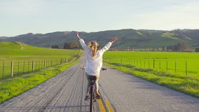 Girl Riding Bike Down Country Road At Sunset With Hands Up In Air  - Powered by Shutterstock - Get 15% off with code: PIKWIZARD15