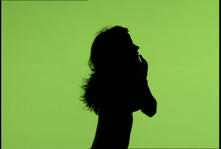 A silhouetted woman dancing against green background