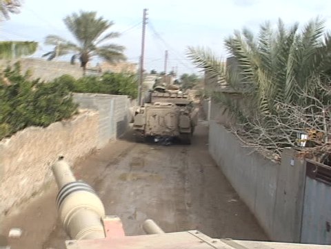 Abrams tanks move through an Iraq village.