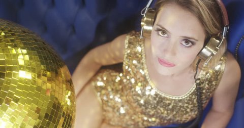 stunning sexy disco woman listening to music on headphones surrounded by disco balls