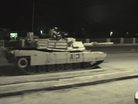 Abrams tanks speed through streets in Iraq.