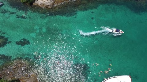 Aerial view of boat maneuvering transparent Caribbean waters and clean at high speed leaving white foam trail on coral in a tropical wild and secluded island, perfect for holiday diving. Ilha Grande.