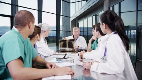 4k / Ultra HD version A diverse team of medical personnel are having a meeting in a light, modern private healthcare facility. They are discussing x-rays and looking for a diagnosis. In slow motion.  Video Stok