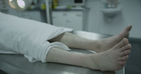 4k / Ultra HD version Smoking kills! Dead male body laid out on an autopsy table with a cigarette in his mouth. Shot on RED Epic