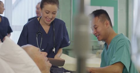 4k / Ultra HD version Nurses attend to an elderly male patient, checking his blood pressure and chatting. In the background a nurse and a specialist are discussing another patient. Shot on RED Epic