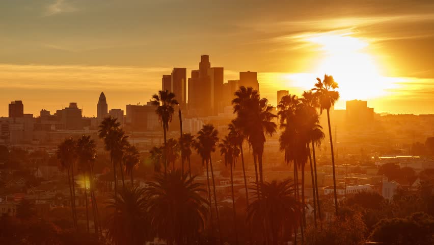 Beautiful sunset to night transition over city of Los Angeles downtown skyline with palm trees in foreground. 4K UHD timelapse.