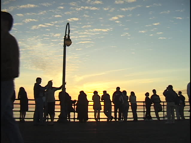 A crowd of people stand on a pier.