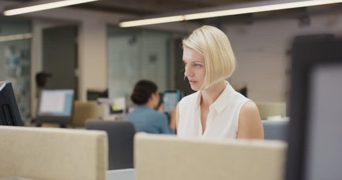 Powerful Businesswoman executive working at computer using smart phone connected to global data in busy corporate office