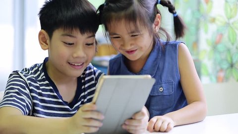 Little asian boy and girl take a photo with tablet computer 