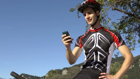Sport and leisure activity: young man riding on bicycle and text messaging on cell phone Stock Video