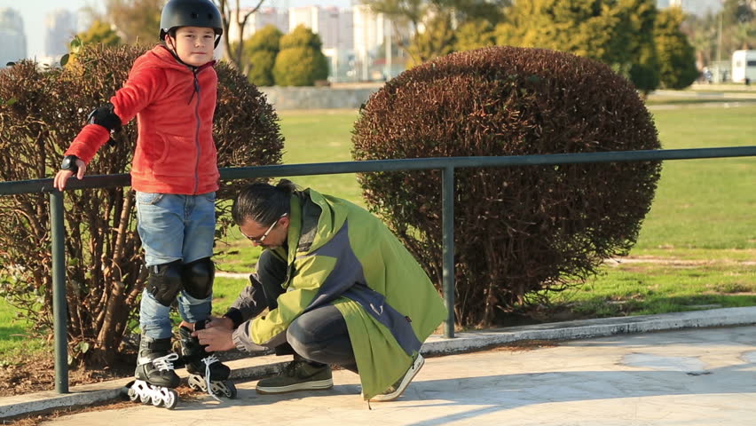 Portrait of a young boy  on the roller skate in the park with his father