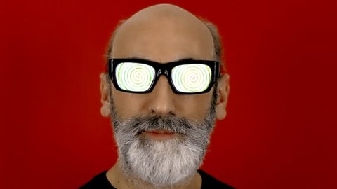 An old man with hypnotic glasses, looking at the viewer while a spiral animation runs into his eyeglasses.