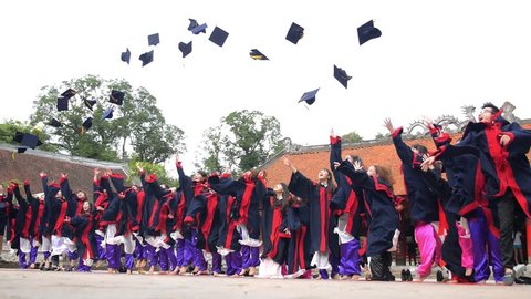 HANOI, VIETNAM - JUL 7, 2015. Cheerful Students Throwing Graduation Caps in the Air