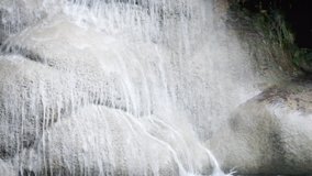 Closeup streaming water of tropical waterfall. Kanchanaburi National Park, Thailand. Seamless looping video with original audio