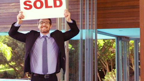 Estate agent cheering and holding SOLD sign in a villa