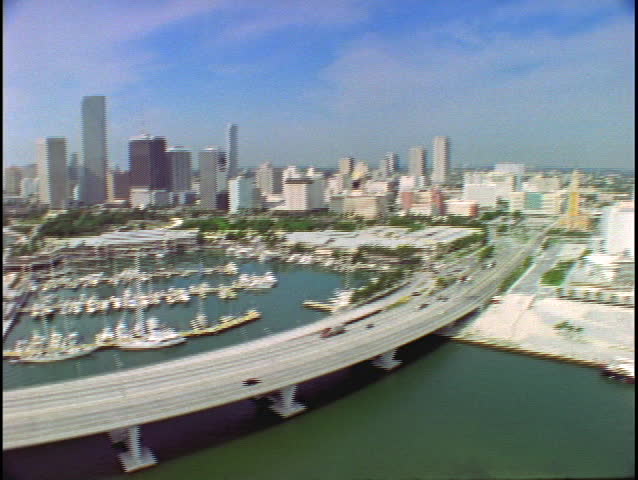 Watercraft dock in a marina and vehicles travel a roadway in Miami, FL.