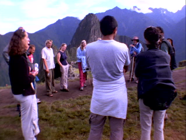 Wide-shot of tourists looking at Inca ruins of Machu Picchu in Peru.