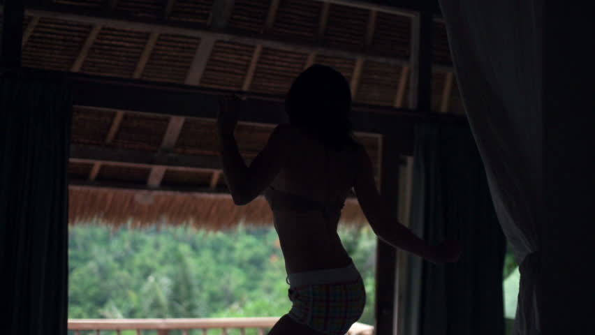 Silhouette of happy woman jumping on bed in house with beautiful terrace view, 240fps
