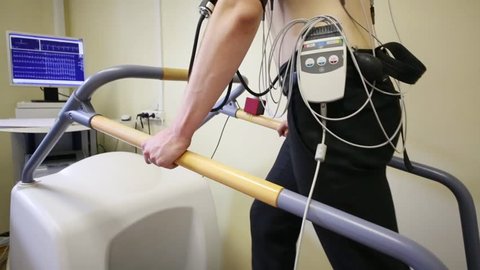Young man walking on a treadmill during the making of electrocardiogram
