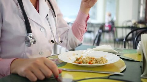 Doctor with stethoscope around her neck dines in a hospital canteen