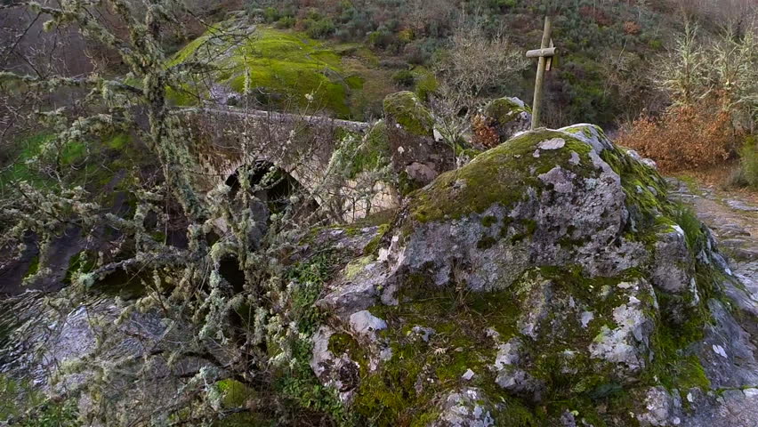 Aerial view of a river on a mountain, with an old bridge